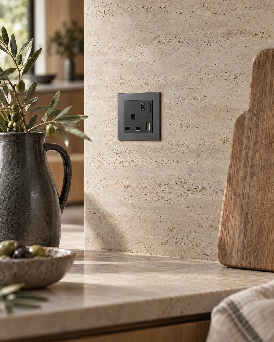 A grey aluminium smart socket set into a travertine kitchen splashback