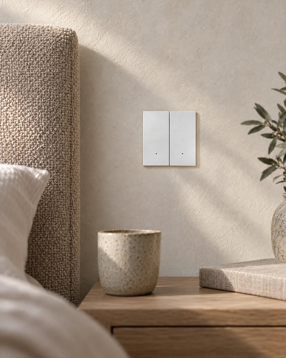 A white aluminium 2-gang smart light switch beside a bed, above an oak bedside table